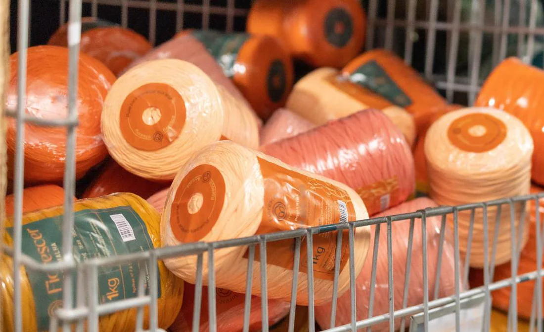 Carrinho de fábrica cheio de rolos de fio de malha em tons de laranja
